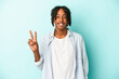 © Asier - Young african american man isolated on blue background showing victory sign and smiling broadly.