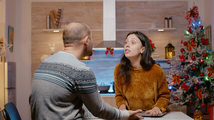 Woman eager to celebrate christmas eve interrupting work meeting on video call for business man. Person working with laptop at home on holiday while wife waiting for seasonal celebration