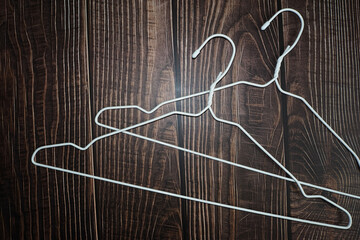 two white metal hangers lie on a brown wooden background. top view