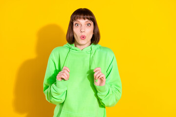 Poster - Photo of amazed cheerful young shocked woman hold hands hoodie sale isolated on yellow color background