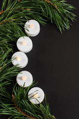 Wall Mural - top view of candles near fir branches isolated on black