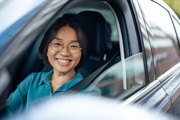 Portrait of a happy Asian businesswoman driving to work.