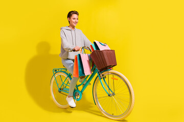 Poster - Full size profile photo of nice brown hair young lady ride bicecly wear sweater jeans sneakers isolated on yellow background