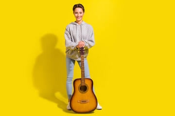 Poster - Full size photo of lovely brown hair young lady with guitar wear sweater jeans sneakers isolated on yellow background