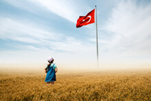 Adorable Baby Girl Is In A Field With Fog And Looking To Turkish National Flag Admiringly.