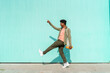 © VISTA by Westend61 - Mid adult man pointing while walking by turquoise wall on sunny day