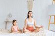 © Вадим Каштанов - Young mother with her little daughter sitting in lotus position. Meditation and relaxation.