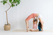 © Вадим Каштанов - Mom and little daughter practice yoga at home. Exercise bridge.