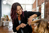 Hairstylist trimming hair of the customer in a beauty salon