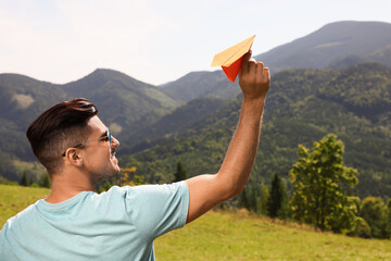 Wall Mural - Man throwing paper plane in mountains on sunny day