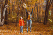 © satura_ - Single parent family playing with autumn leaves in park. Happy mom and son throw autumn leaves up in fall park.