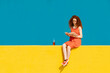 © VISTA by Westend61 - Young redhead woman reading book while sitting on yellow retaining wall