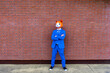 © VISTA by Westend61 - Man wearing vibrant blue suit and cat mask standing with crossed arms in front of brick wall