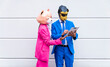 © VISTA by Westend61 - Man and woman wearing vibrant suits and animal masks talking over clipboard in front of white wall