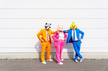 Three People Wearing Vibrant Suits And Animal Masks Posing Side By Side In Front Of White Wall