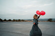 © VISTA by Westend61 - Mid adult woman holding balloon while dancing on road