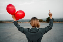 Blond Woman Holding Balloon And Showing Obscene Gesture At Road