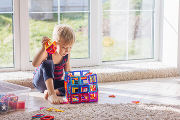 The child is playing with a multi-colored magnetic constructor, building a tower. Educational toys . A building block for a baby or toddler kid Clutter in the playroom