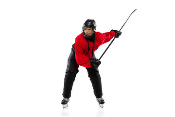 Full-length portrait of woman, professional hockey player in motion with raised stick, training isolated over white background.