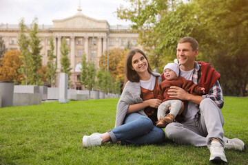 Sticker - Happy parents with their adorable baby on green grass in park