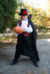 Wall Mural - a boy in a Halloween costume holding an orange pumpkin