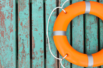 Orange life buoy on turquoise wooden background, top view. Space for text