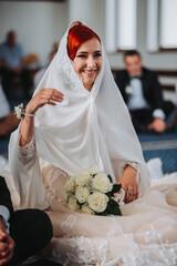 Poster - Vertical shot of the red-haired bride sitting at the altar in a veil holding her bouquet