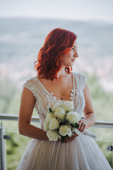 Wall Mural - Vertical shot of the red-haired bride in a gorgeous dress holding her bouquet