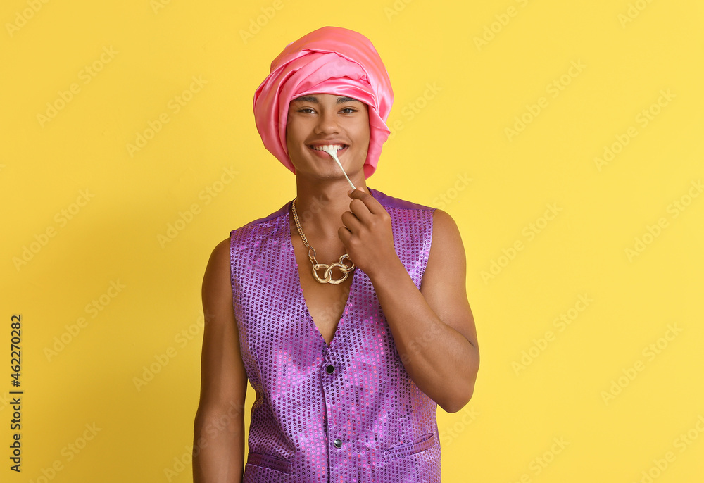 Glamorous African-American guy with chewing gum on color background