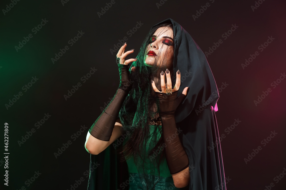 Beautiful woman dressed as witch for Halloween party on dark background
