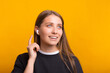Beautiful woman is wearing some wireless ear pods over yellow background.
