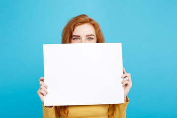 Wall Mural - Close up Portrait young beautiful attractive redhair girl smiling showing blank sign. Blue Pastel Background. Copy space.