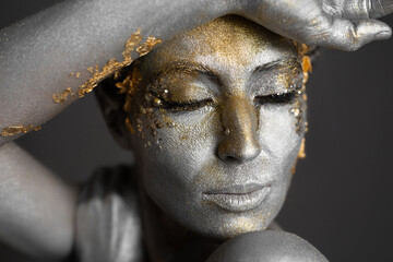 Wall Mural - Portrait of a beautiful female model with gold and silver paint on her skin and hair in the studio.