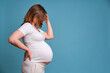 © Андрей Журавлев - Emotion of worries and problems in a pregnant woman, studio shot on a blue background