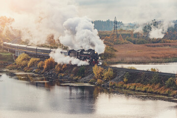 Wall Mural - Retro steam train moves along the lake at autumn sunrise.