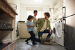 © Southworks - Father and sons loading washing machine in kitchen
