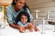 © Southworks - Mother helping young son wash hands in sink