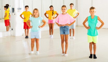 Wall Mural - Young boys and girls standing with hands on their waists in dance studio.