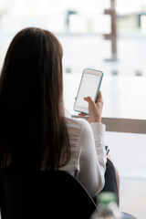 Wall Mural - young asian woman holding blank screen smartphone while sitting in office room
