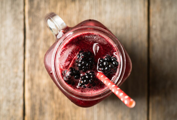 Wall Mural - Blackberry cocktail with crushed ice in glass jar on the rustic wooden background. Selective focus. Shallow depth of field.