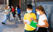 Leinwandbild Motiv Portrait of primary school girl and boy wearing protective face masks talking outside before lesson, new normal during coronavirus pandemic situation