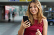 © zigres - Close-up of charming beautiful business woman smile in casual style using smartphone walking in train or metro station. Copy space.