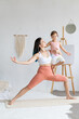 © Вадим Каштанов - Young woman practices yoga in warrior pose with her daughter. Children's yoga.