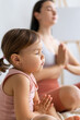 © Вадим Каштанов - Young mom practices yoga with her little daughter. Meditation in lotus position.