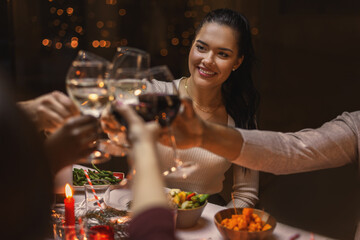 Wall Mural - holidays, party and celebration concept - multiethnic group of happy friends having christmas dinner at home and drinking wine