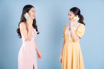 Two young Asian women wearing dress on blue background