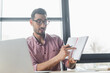 © LIGHTFIELD STUDIOS - Arabian businessman in eyeglasses pointing at notebook during video chat on blurred laptop in office