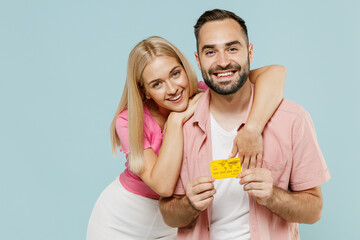 Young couple two friends family man woman in casual clothes hold in hand credit bank card hug together isolated on pastel plain light blue color background studio portrait People lifestyle concept