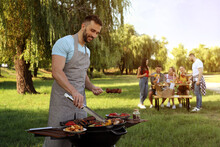 Man Cooking Meat And Vegetables On Barbecue Grill In Park