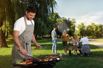 Canvas Print - Man cooking meat and vegetables on barbecue grill in park